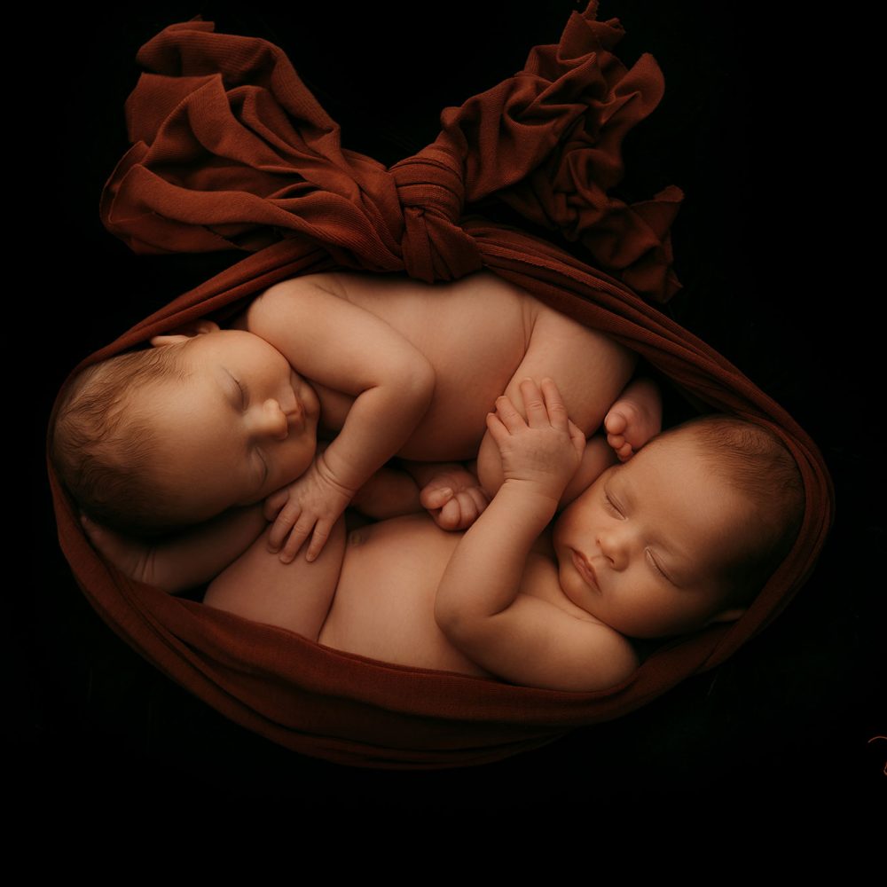Neugeborene Zwillinge schlafen aneinander gekuschelt